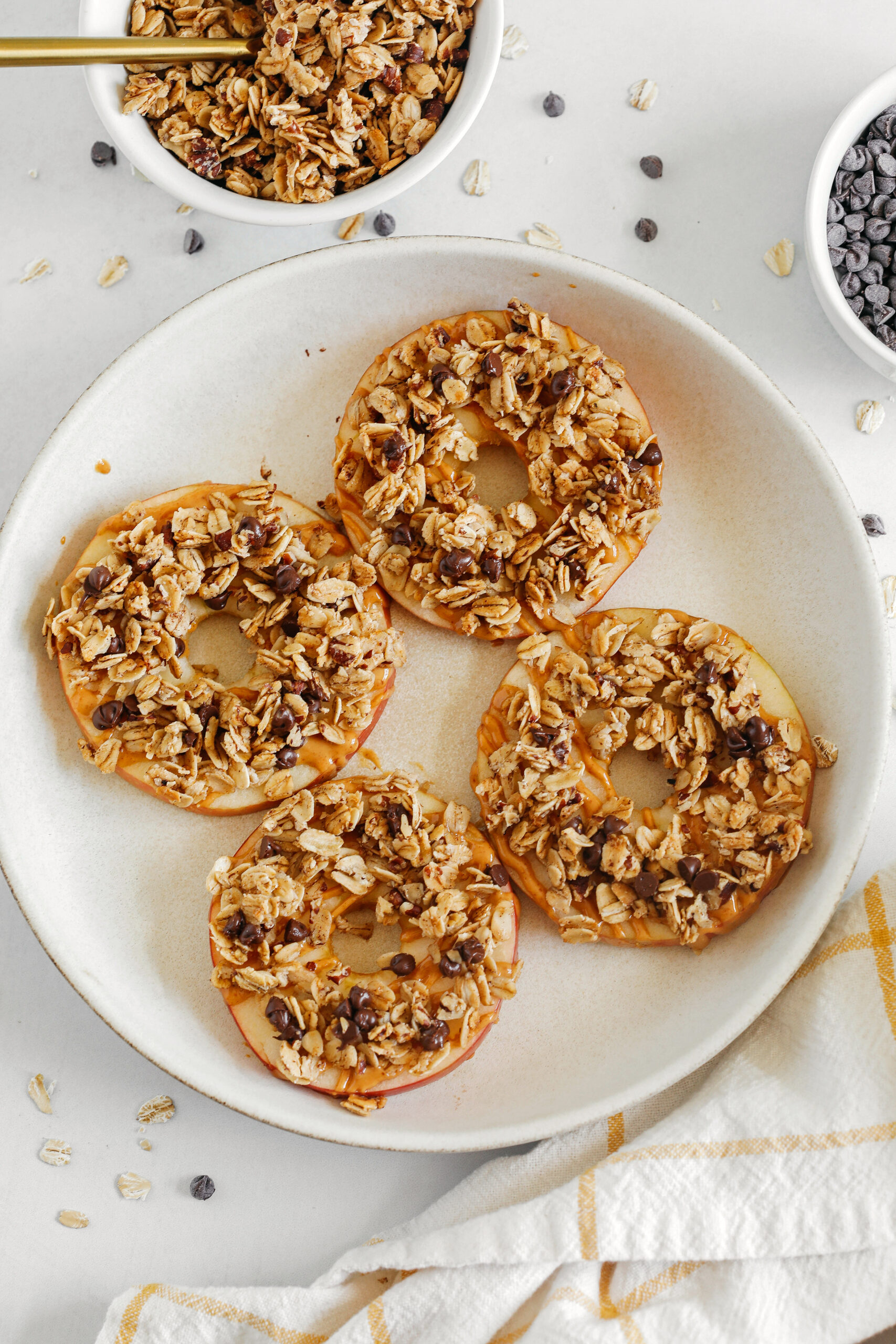 These delicious Peanut Butter Granola Apple Rings make the perfect after-school snack or fun dessert!  Sliced apples drizzled with drippy peanut butter and sprinkled with homemade cinnamon pecan granola studded with chocolate chips!
