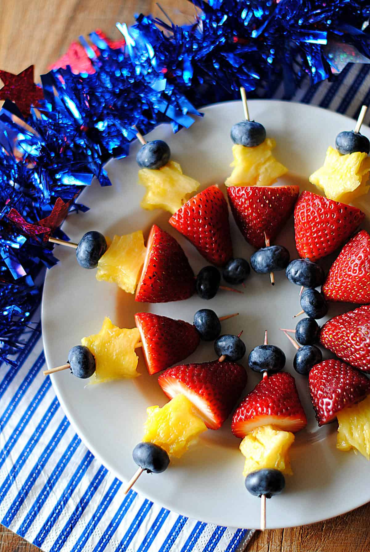 Red white and blue fruit skewers with strawberries marshmallows and blueberries on a platter for 4th of July