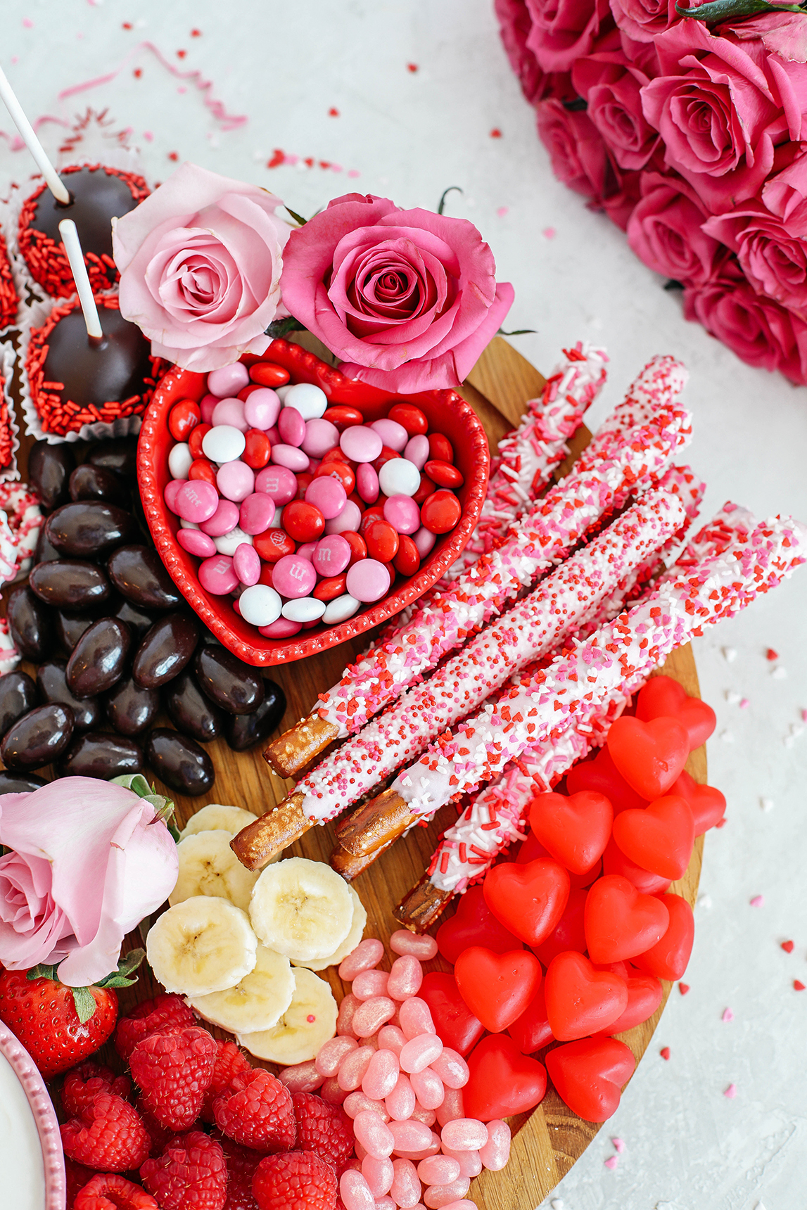 Celebrate Valentine's Day with a fun and festive dessert board made with healthier options like yogurt-dipped pretzels, chocolate covered almonds, fresh fruit and a honey yogurt dipping sauce!