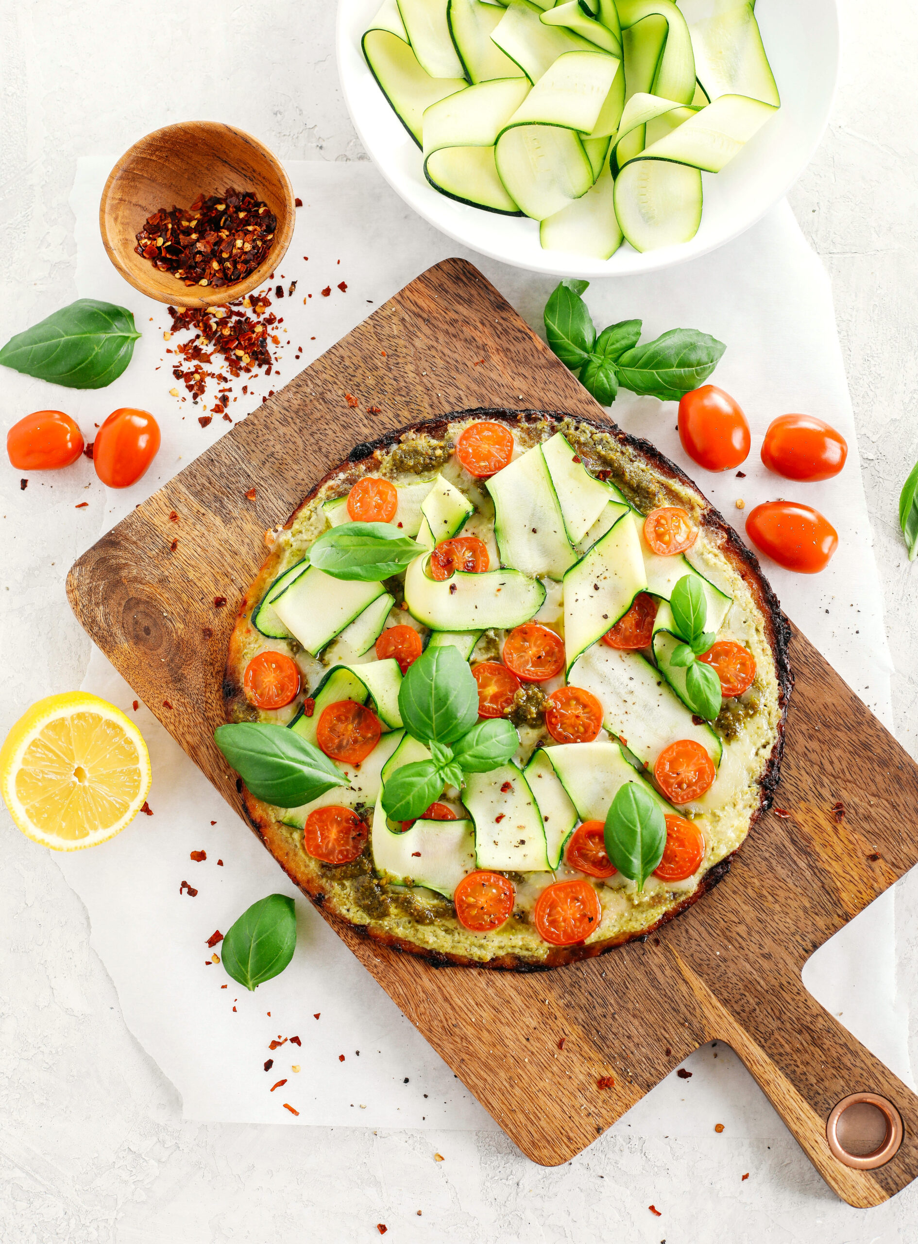 Garden Pesto Cauliflower Pizza loaded with fresh tomatoes, zucchini, homemade basil pesto and ricotta all topped on a crispy cauliflower crust for a delicious low carb meal in just 15 minutes!