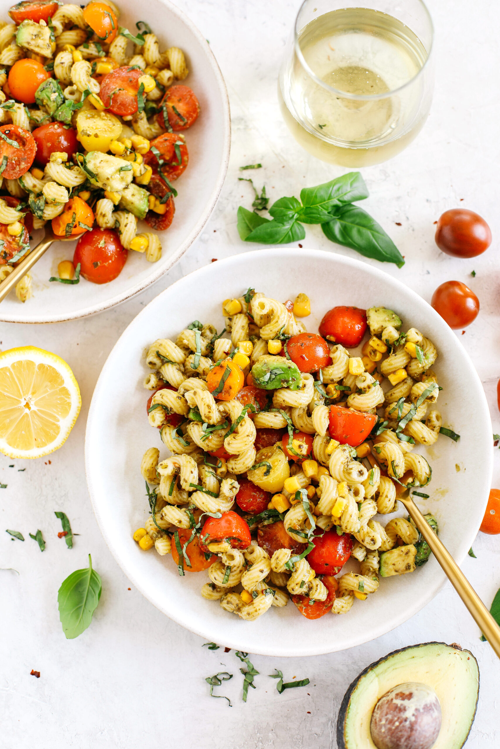 This EASY 10-minute Summer Pesto Pasta Salad is loaded with fresh ingredients like juicy tomatoes, corn, avocado, garlic, and lemon zest, all tossed together with warm pasta and delicious basil pesto!