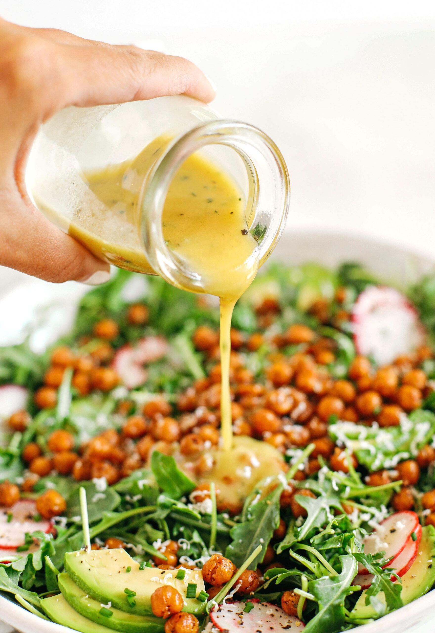 The most delicious Arugula Salad with Honey Roasted Chickpeas that are sweet, savory and perfectly crunchy!  Top with fresh veggies, avocado slices and my lemon dijon herb dressing!