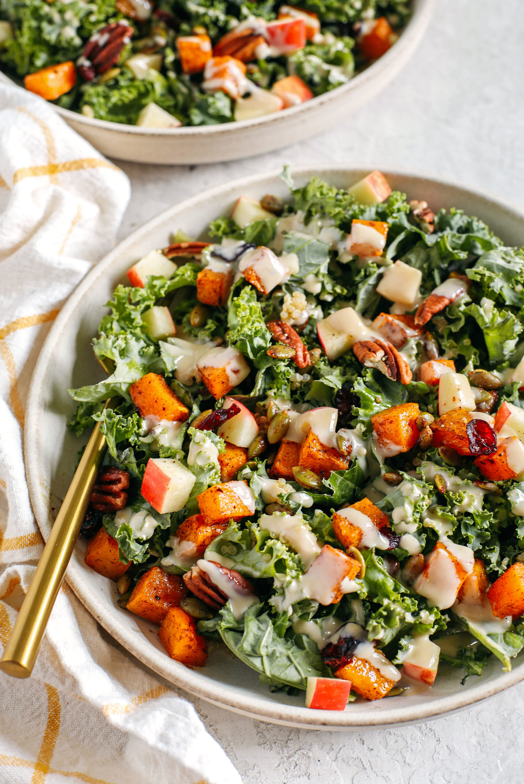 The ultimate powerhouse Fall Salad made with leafy kale, protein-packed quinoa, crisp apples, roasted butternut squash, spiced pepitas and pecans, all drizzled in the most delicious maple tahini dressing!