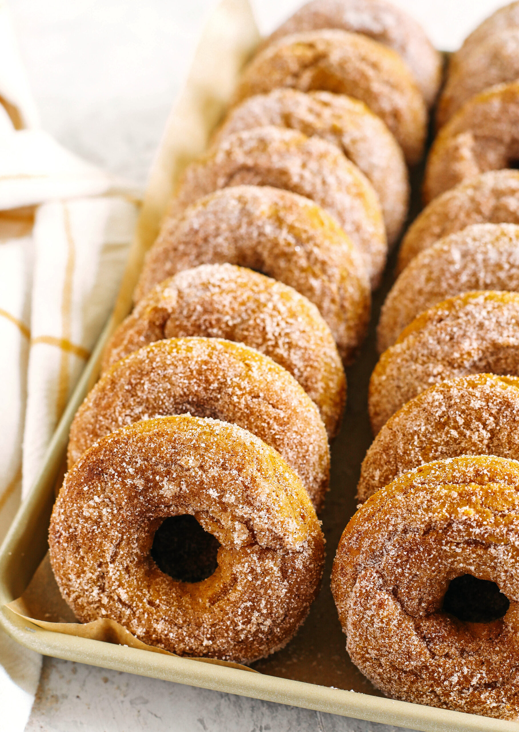 Delicious Gluten-Free Pumpkin Spice Donuts that are soft, lightly sweetened with maple syrup and baked, not fried, for the perfect fall treat!  Loaded with warm spices and coated with cinnamon and sugar!