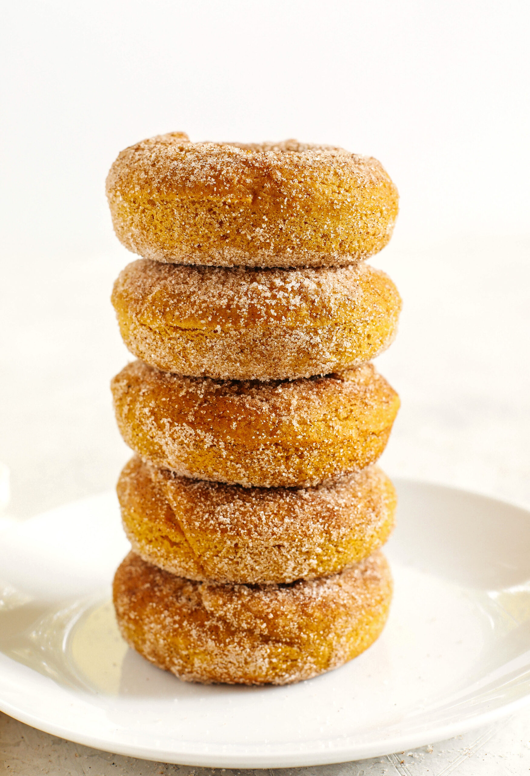 Delicious Gluten-Free Pumpkin Spice Donuts that are soft, lightly sweetened with maple syrup and baked, not fried, for the perfect fall treat!  Loaded with warm spices and coated with cinnamon and sugar!