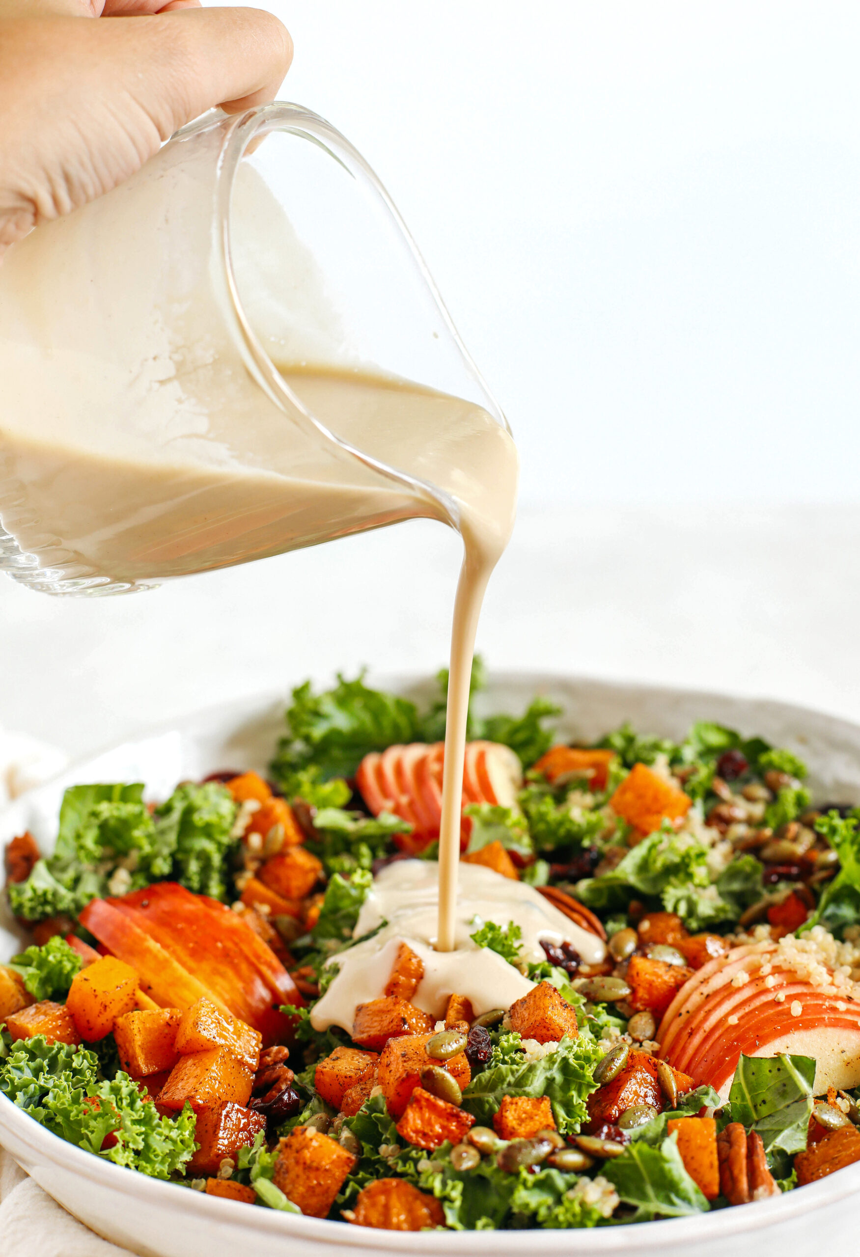 The ultimate powerhouse Fall Salad made with leafy kale, protein-packed quinoa, sliced apples, roasted butternut squash, and spiced pepitas and pecans, all drizzled in the most delicious maple tahini dressing!