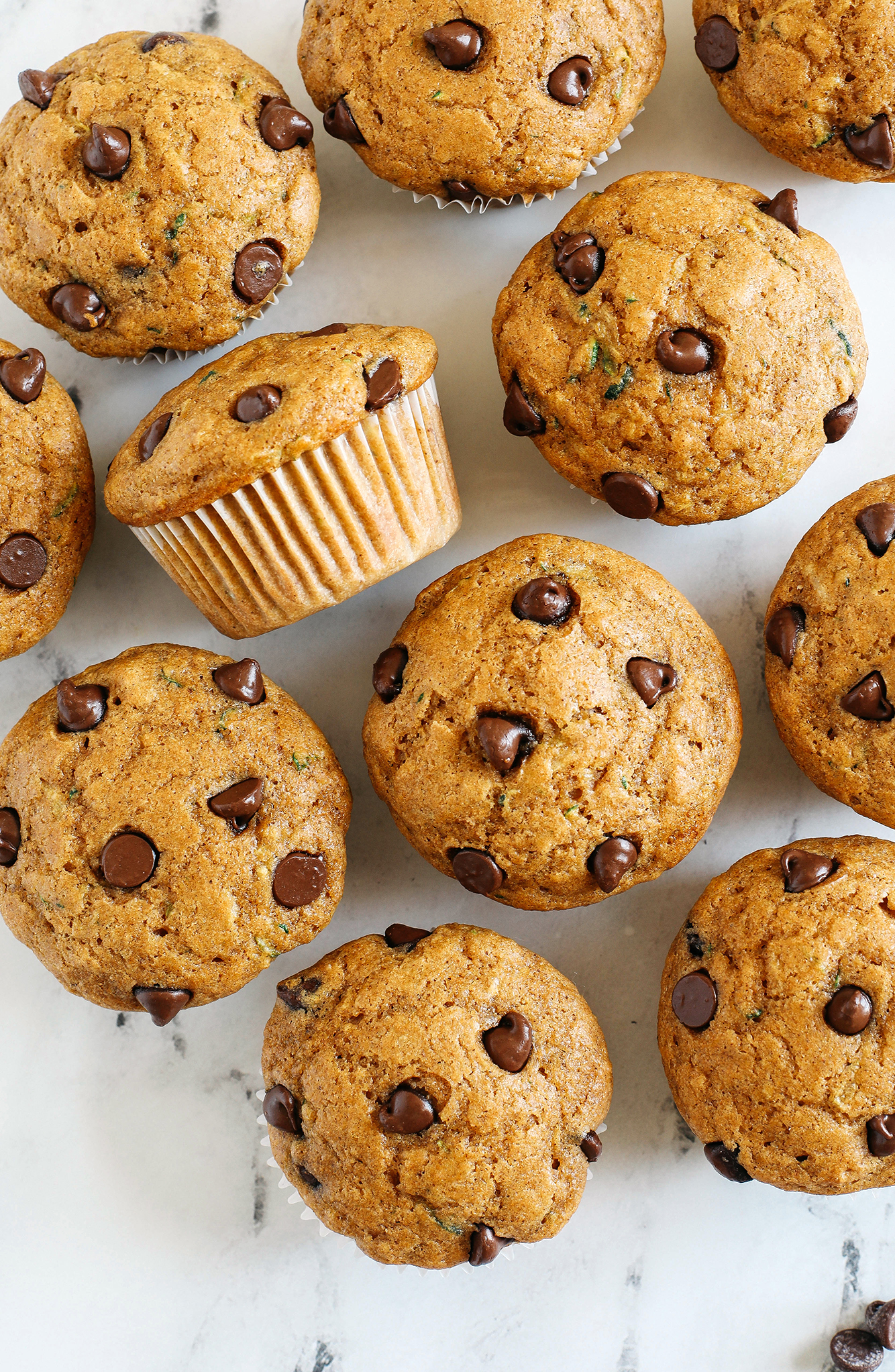 These Chocolate Chip Zucchini Muffins are moist, fluffy, and made healthier with whole wheat flour, Greek yogurt, shredded zucchini and zero butter or refined sugar.  Loaded with warm flavors and chunks of chocolate in every bite!