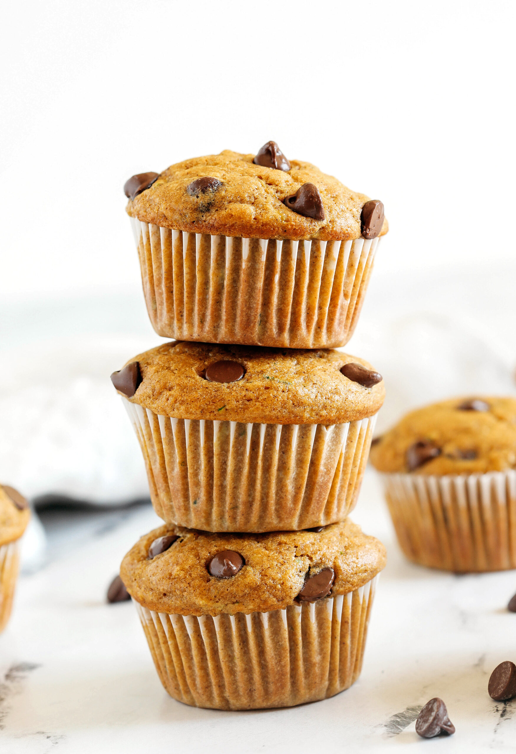 These Chocolate Chip Zucchini Muffins are moist, fluffy, and made healthier with whole wheat flour, Greek yogurt, shredded zucchini and zero butter or refined sugar.  Loaded with warm flavors and chunks of chocolate in every bite!