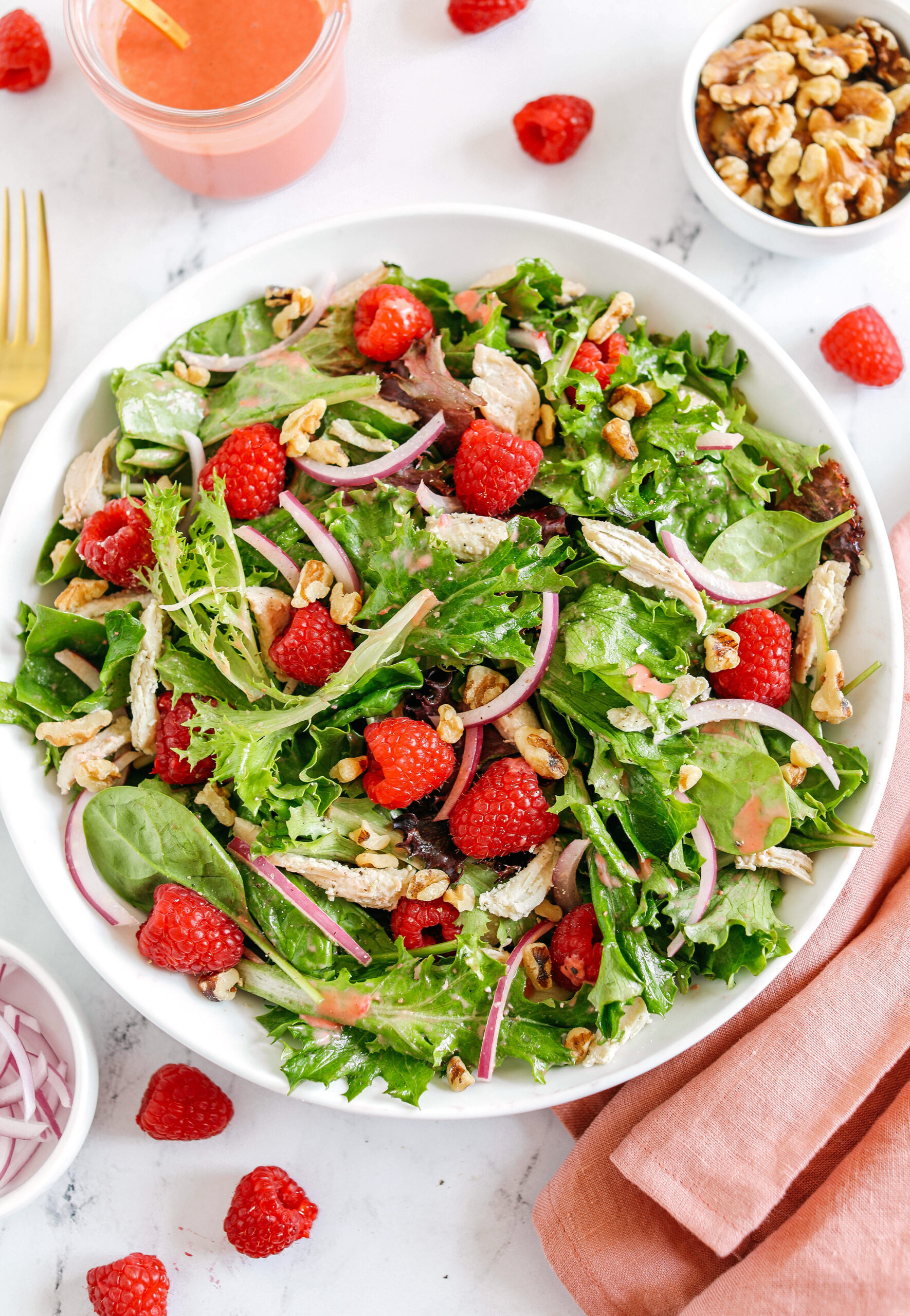 My favorite Raspberry Walnut Salad with Chicken made with leafy greens, fresh raspberries, shredded chicken, chopped walnuts, and sliced red onion all tossed with a creamy raspberry vinaigrette!