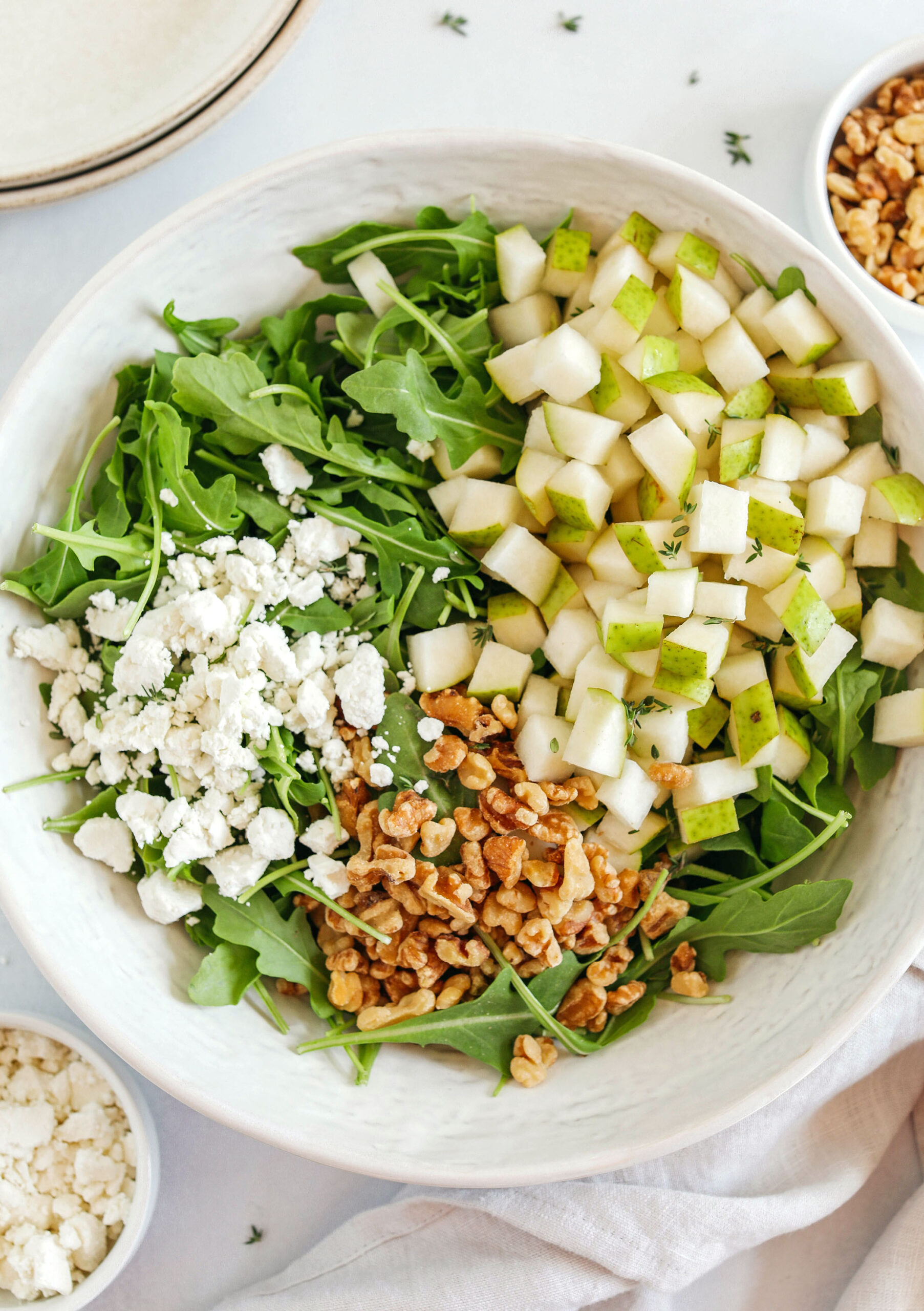This simple Pear and Arugula Salad is made with fresh arugula, chopped pears, creamy goat cheese and crunchy pecans all tossed with a bright and lemony honey vinaigrette!  The perfect fall salad that is super easy to throw together!