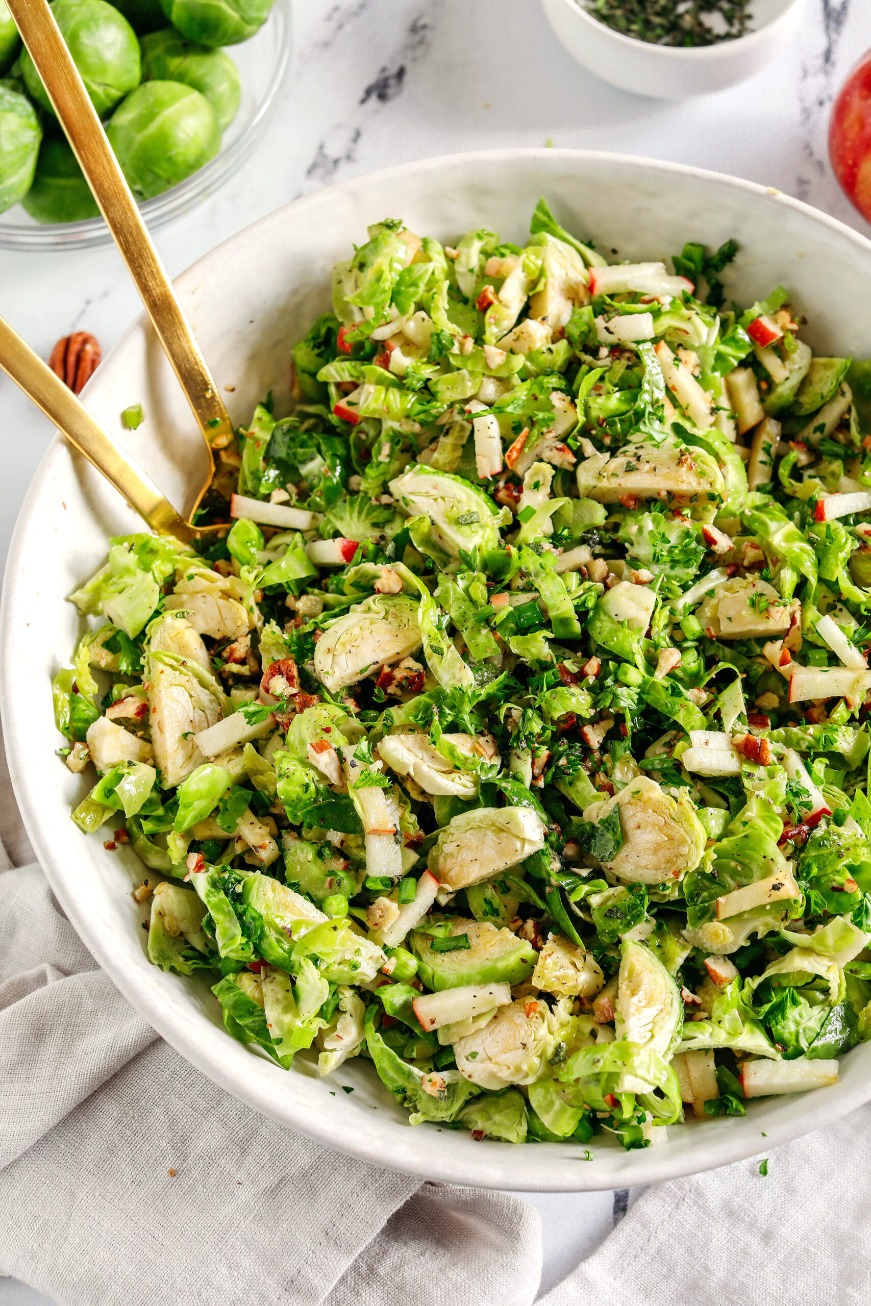 The most delicious Fall Brussels Sprout Salad made with shaved brussels sprouts, chopped apples and crunchy pecans all tossed with a maple dijon dressing!  This salad makes a great side dish for the holidays or everyday meals.