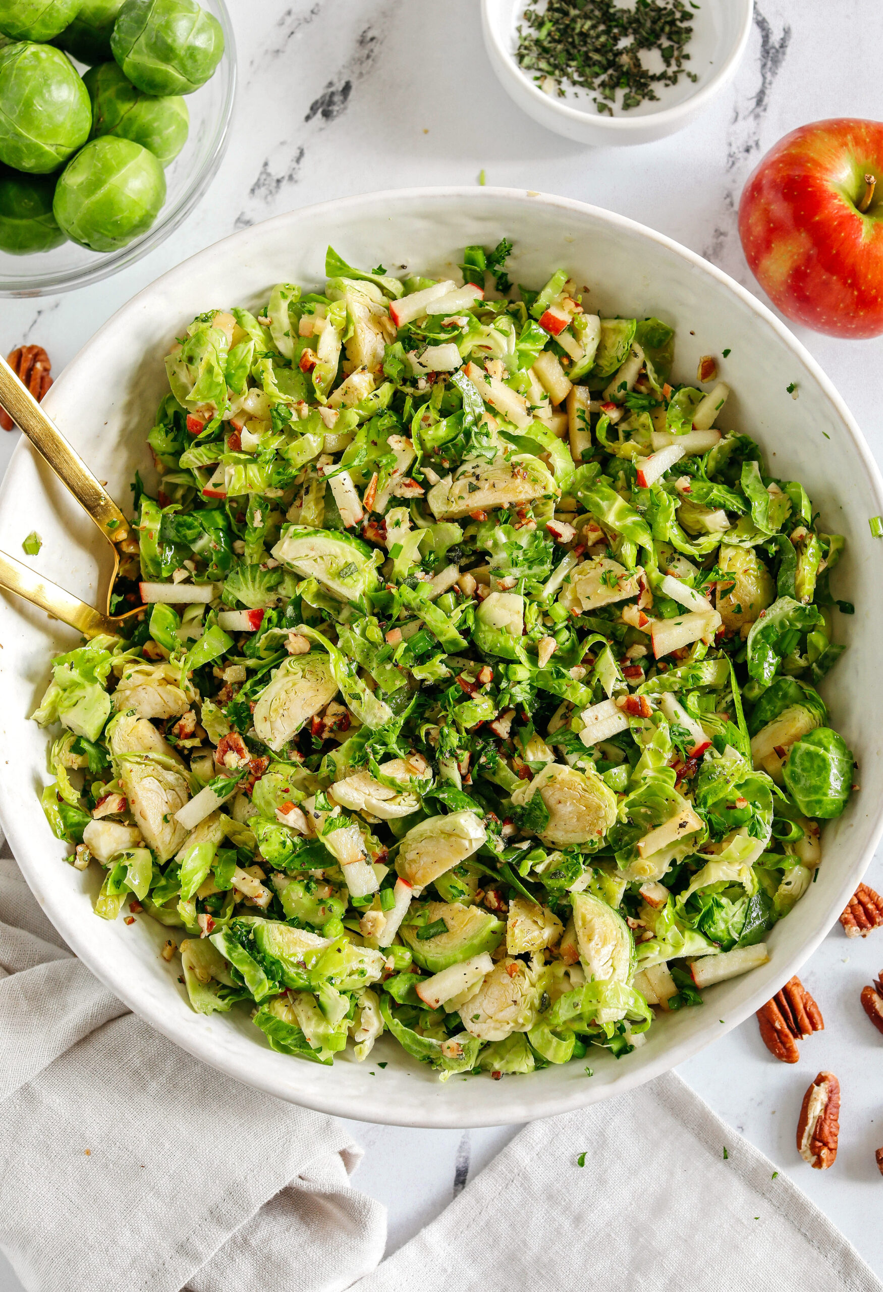 The most delicious Fall Brussels Sprout Salad made with shaved brussels sprouts, chopped apples and crunchy pecans all tossed with a maple dijon dressing!  This salad makes a great side dish for the holidays or everyday meals.