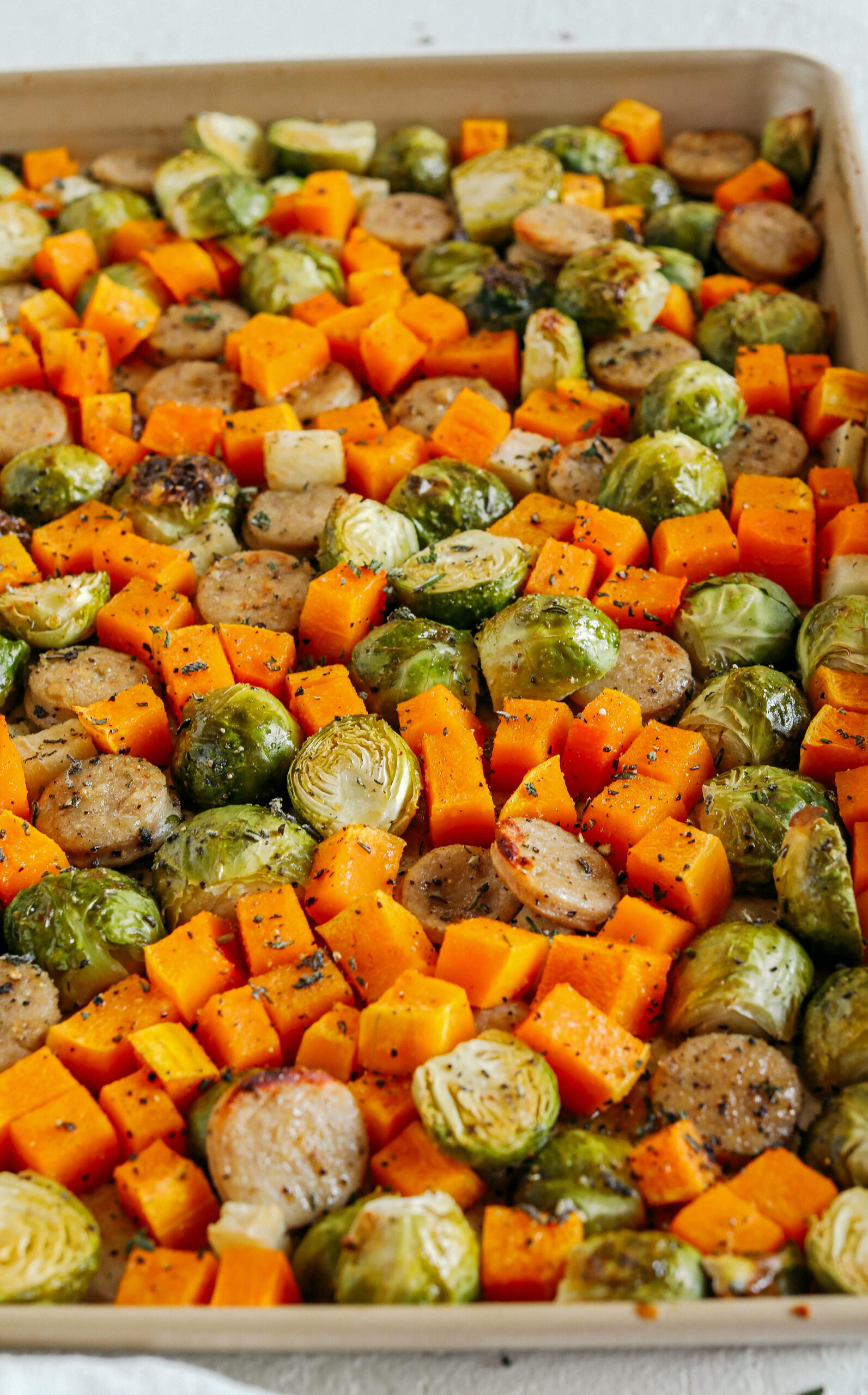 Harvest Sheet Pan Sausage and Veggies loaded with flavorful chicken sausage, butternut squash, brussels sprouts, and apples for a quick and easy dinner made in just 30 minutes!  Roasted in a maple mustard glaze and fresh herbs for the perfect fall meal!  