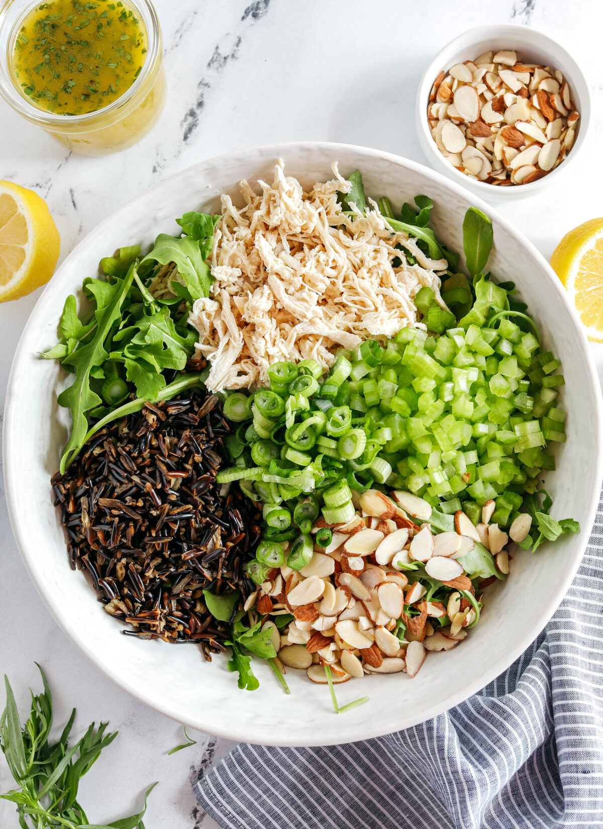 Hearty and delicious Wild Rice Chicken Salad made with leafy arugula, warm wild rice, shredded chicken, sliced almonds, and green onions all tossed with a bright lemon tarragon vinaigrette!