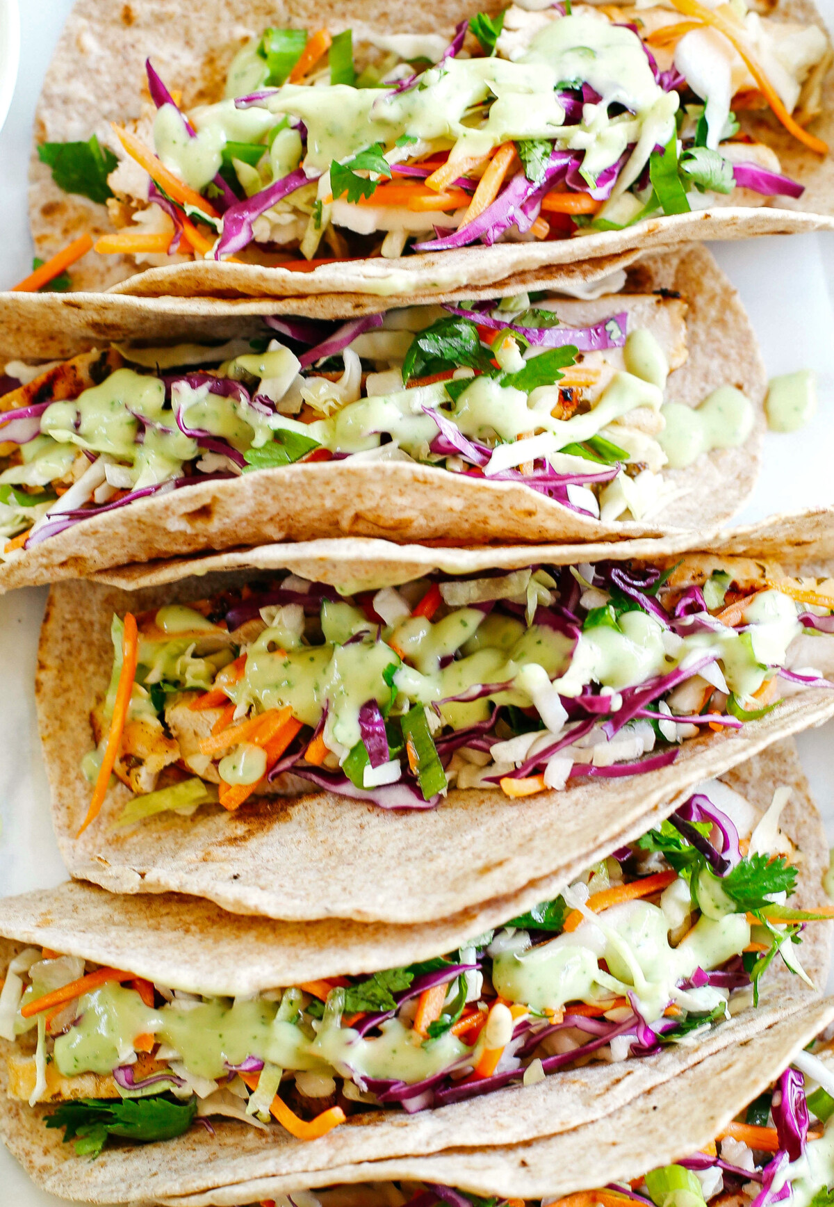 Easy and delicious Cilantro Lime Chicken Tacos topped with tangy coleslaw and homemade avocado crema make the perfect EASY summer recipe!  Full of fresh flavors and healthy ingredients!