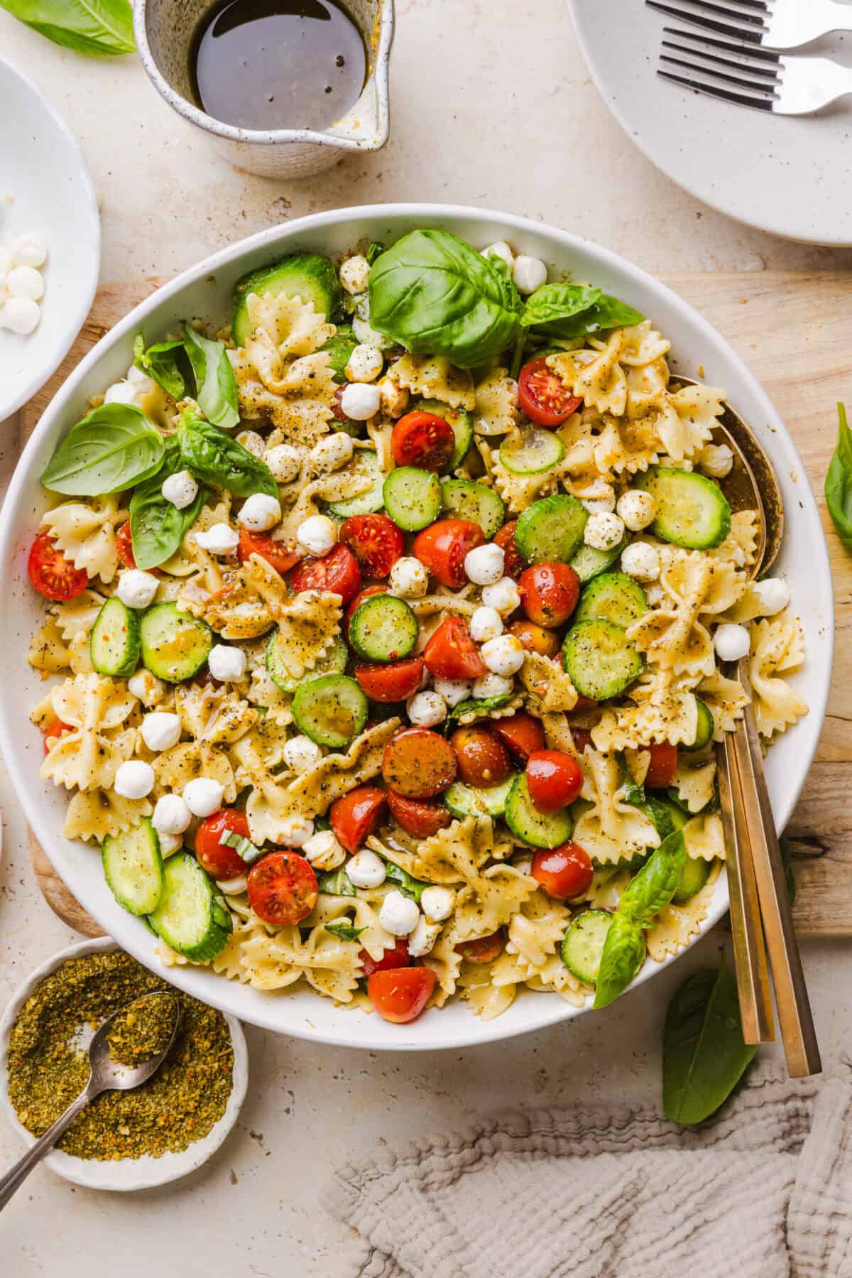 This Easy Caprese Pasta Salad is loaded with fresh tomatoes, mozzarella pearls, fresh basil, cucumbers, and a delicious homemade herb vinaigrette. The perfect make-ahead summer side dish for BBQs, lunches and meal prep!