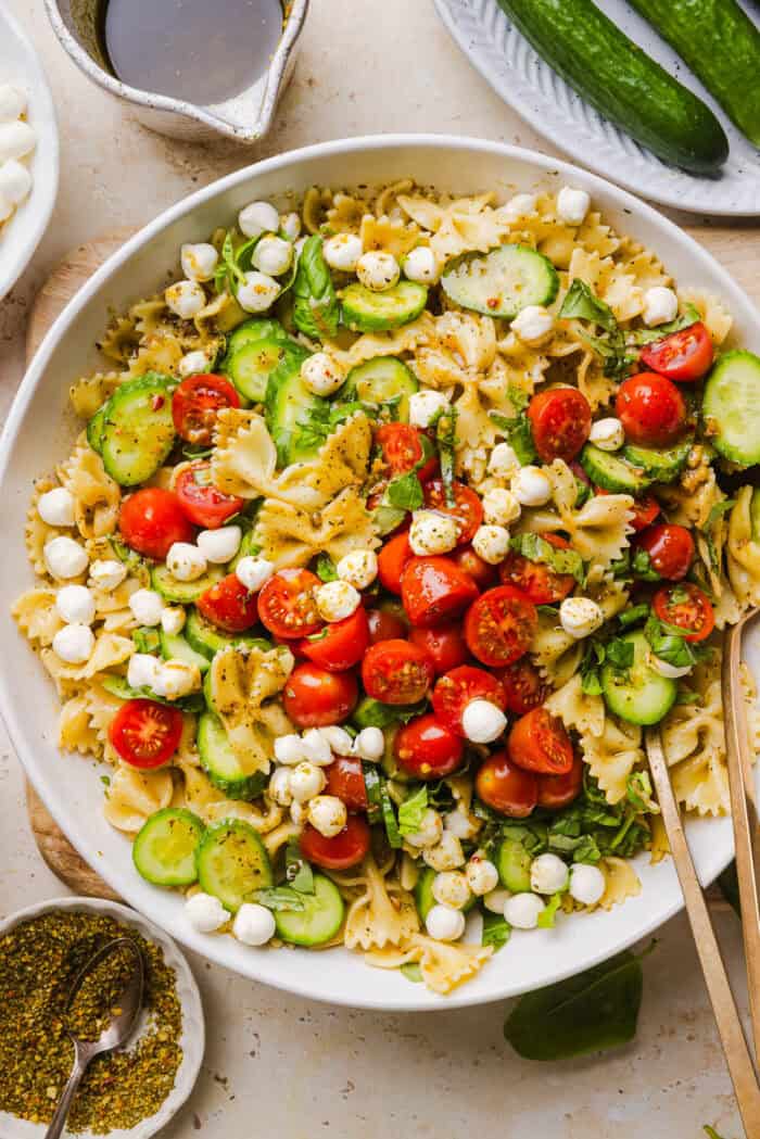 This Easy Caprese Pasta Salad is loaded with fresh tomatoes, mozzarella pearls, fresh basil, cucumbers, and a delicious homemade herb vinaigrette. The perfect make-ahead summer side dish for BBQs, lunches and meal prep!