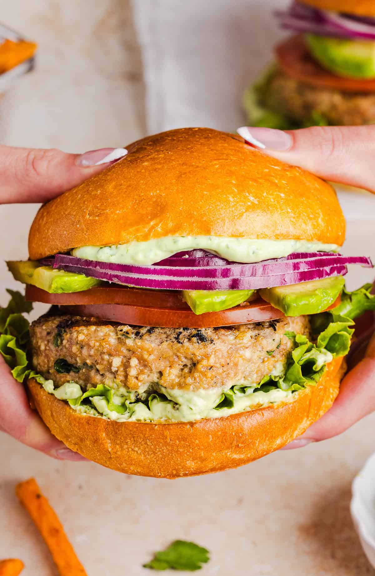 These Cilantro Lime Chicken Burgers are juicy, flavorful, and topped with a creamy avocado cilantro sauce. Made with lean ground chicken, fresh cilantro, green onions, and lime zest, these burgers are perfect for summer grilling or an easy weeknight meal!