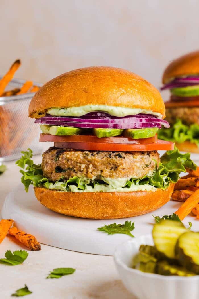 These Cilantro Lime Chicken Burgers are juicy, flavorful, and topped with a creamy avocado cilantro sauce. Made with lean ground chicken, fresh cilantro, green onions, and lime zest, these burgers are perfect for summer grilling or an easy weeknight meal!