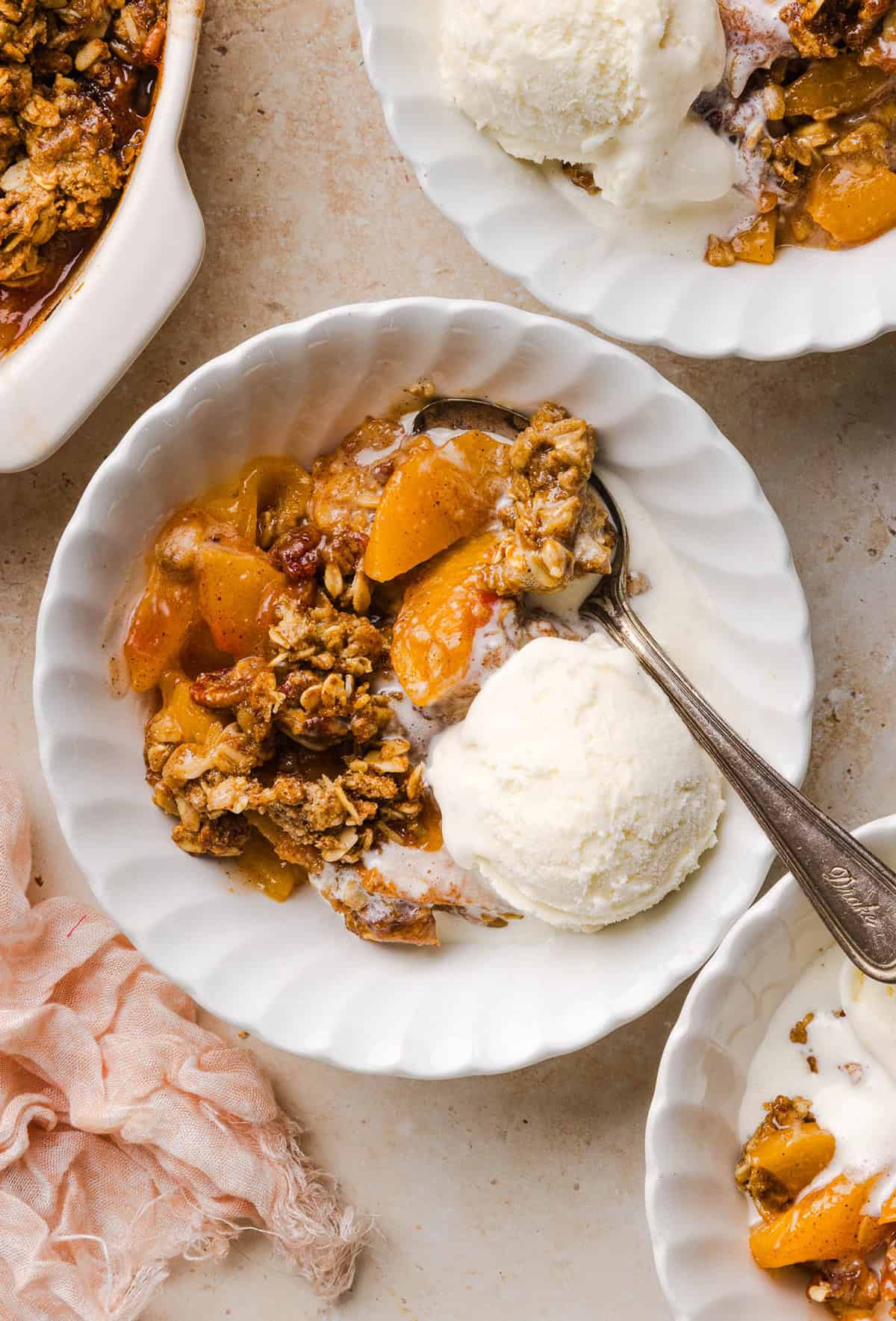 This Healthy Peach Crisp recipe is made with juicy fresh peaches and a wholesome oat pecan crumble naturally sweetened with maple syrup. An easy summer dessert that is warm, cozy, and perfect with vanilla ice cream!
