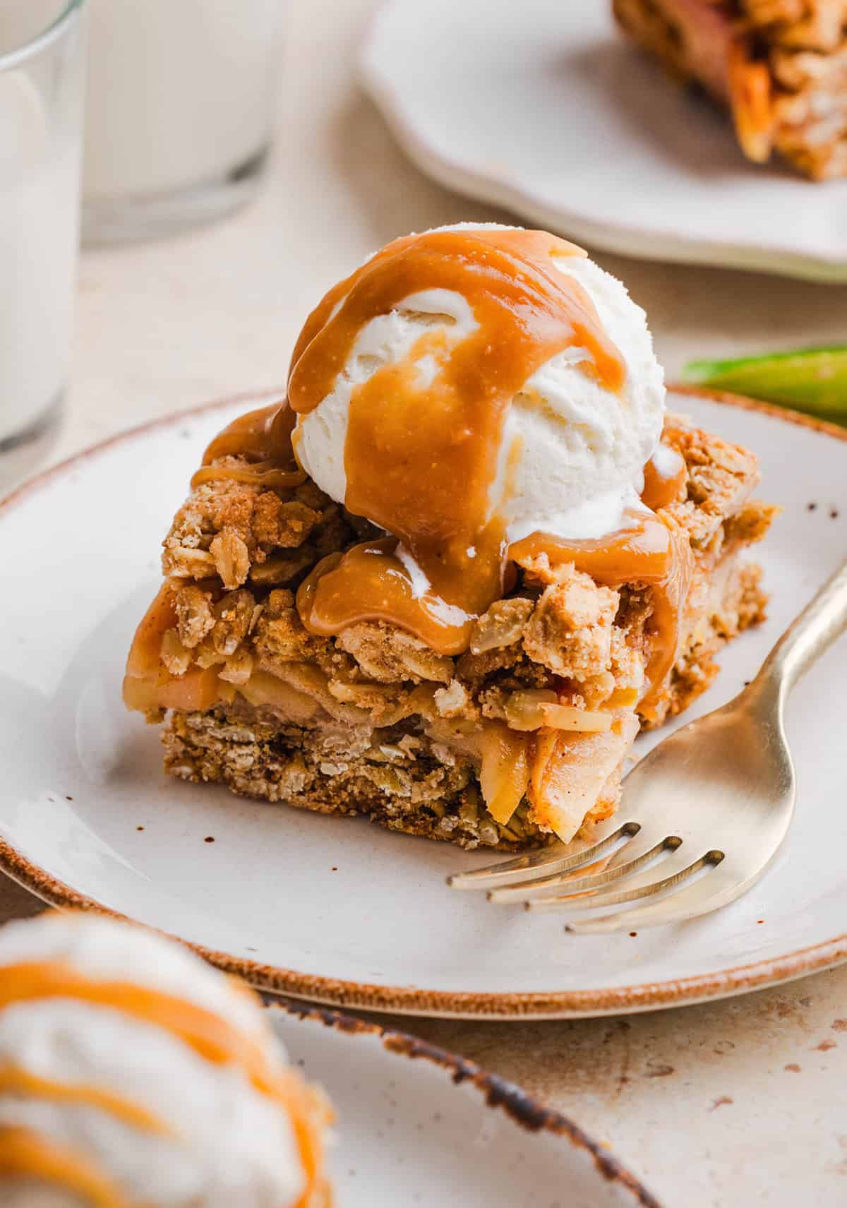 Healthy apple pie crumble bars topped with a scoop of vanilla ice cream and maple caramel drizzle.