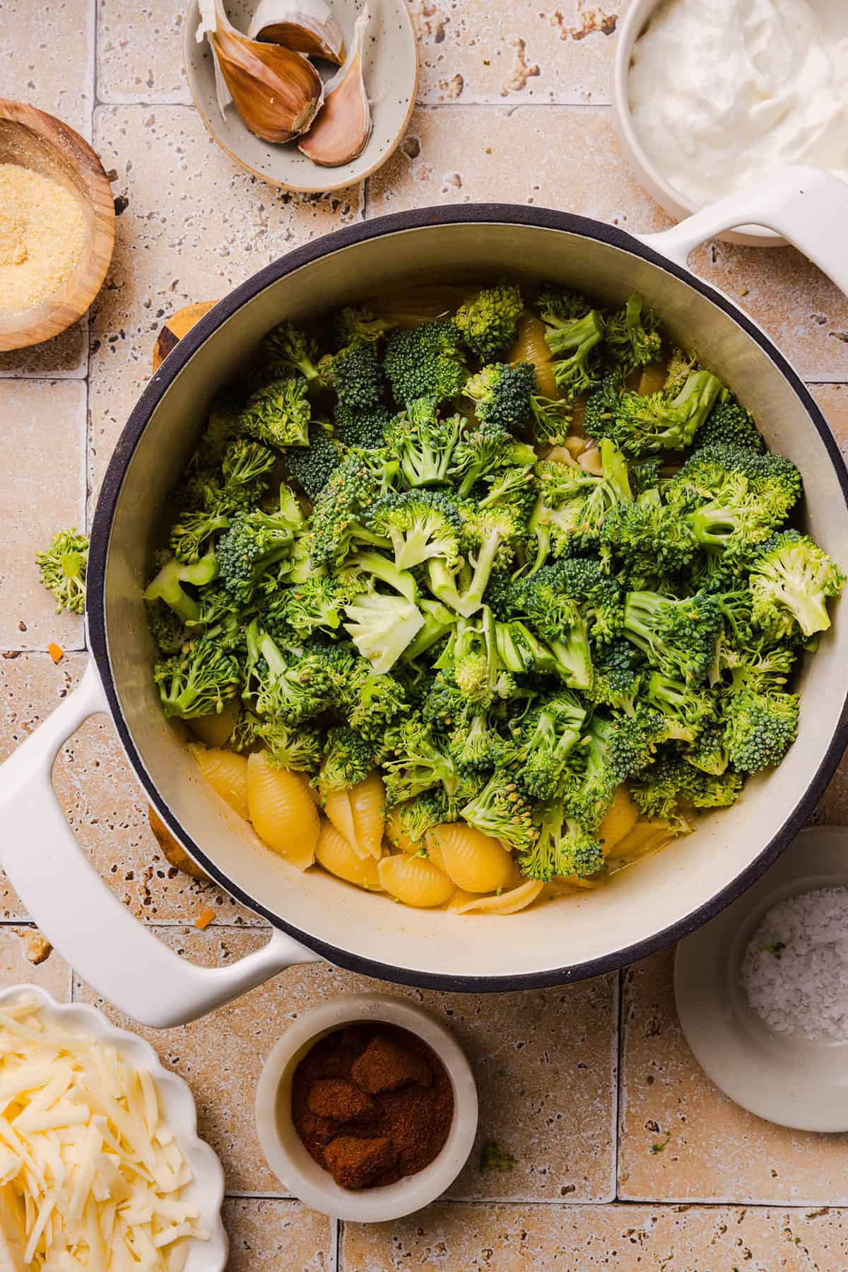 Tender pasta shells in a pot with added chopped broccoli.